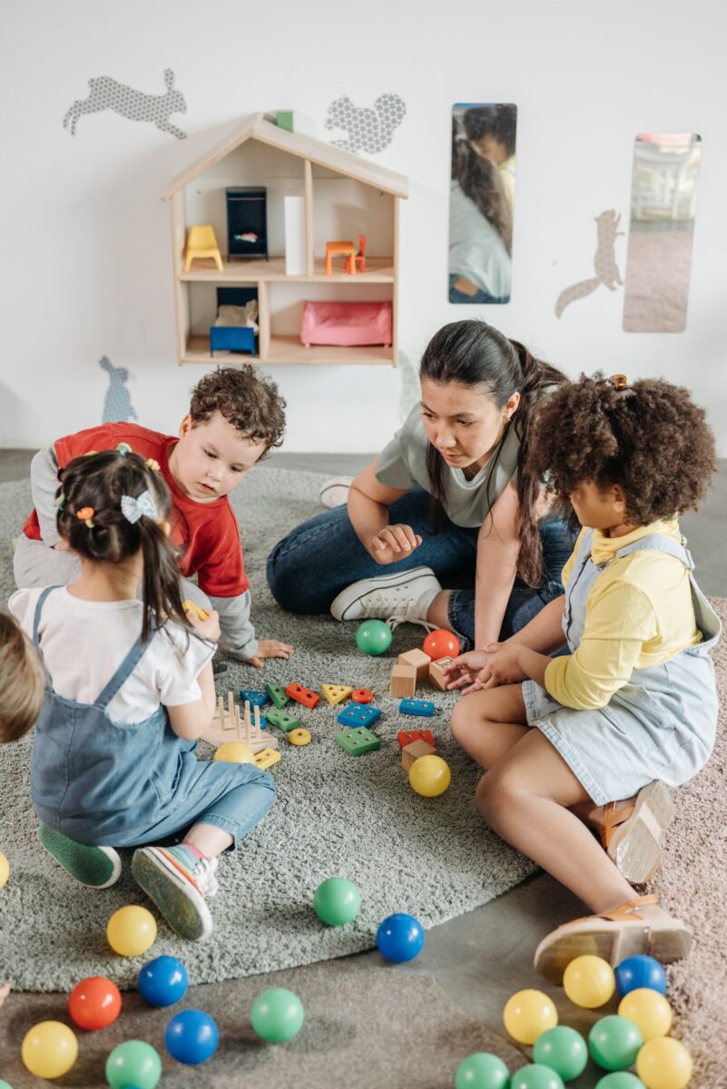 Kids and teacher engaging with toys and activities in a colorful kindergarten.